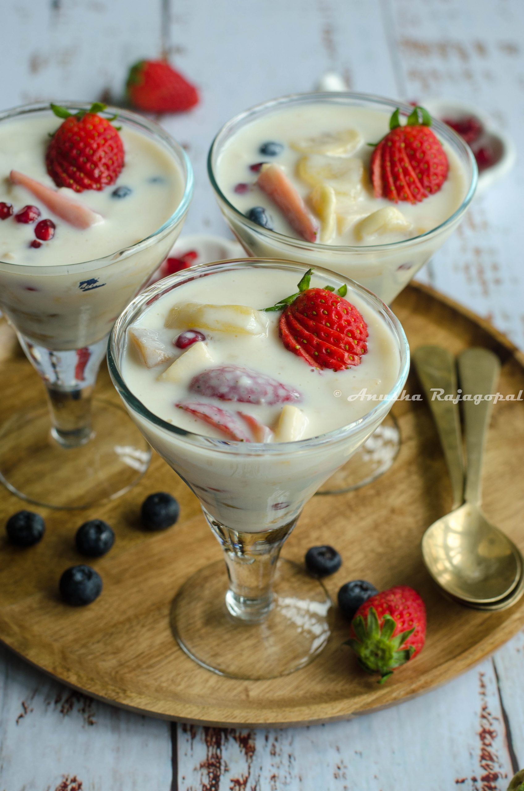 fruit custard without custard powder served in glasses placed on a wooden plate