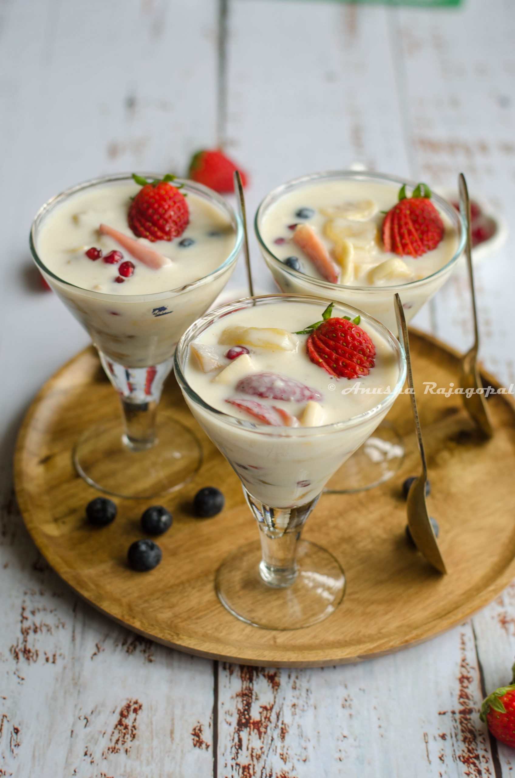 fruit custard without custard powder served in glasses placed on a wooden plate