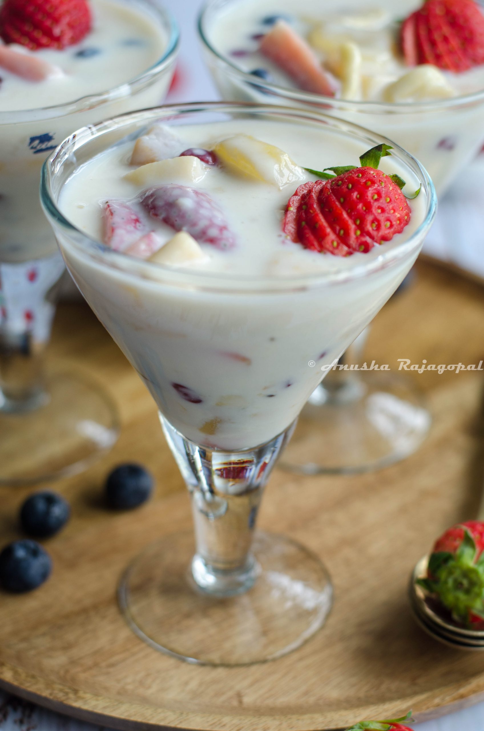 fruit custard without custard powder served in glasses placed on a wooden plate