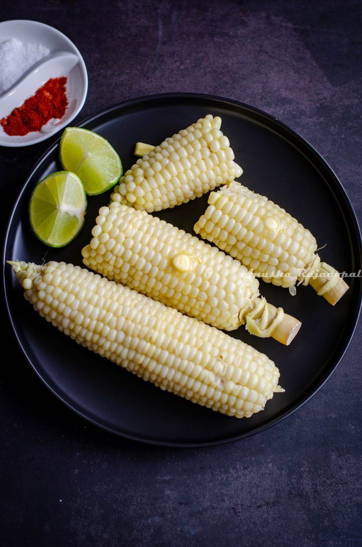 corn on the cob made in the instant pot and served on a black plate. Lime wedges, paprika and salt by the side