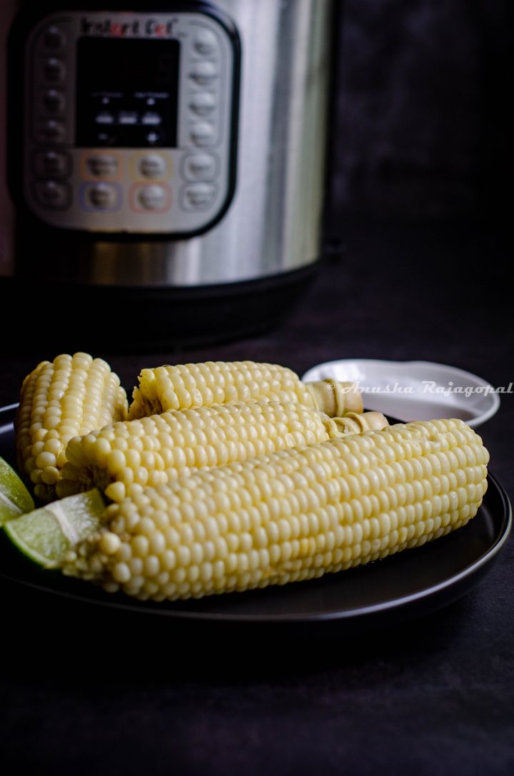 corn on the cob made in the instant pot and served on a black plate. IP in the background