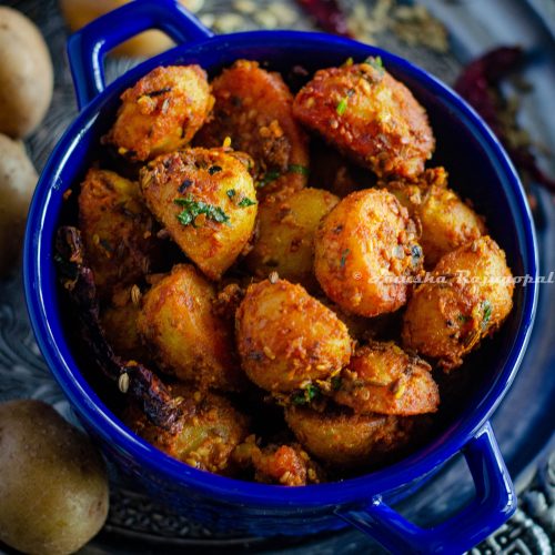 Jodhpuri aloo served in a blue casserole bowl placed over a silver plate