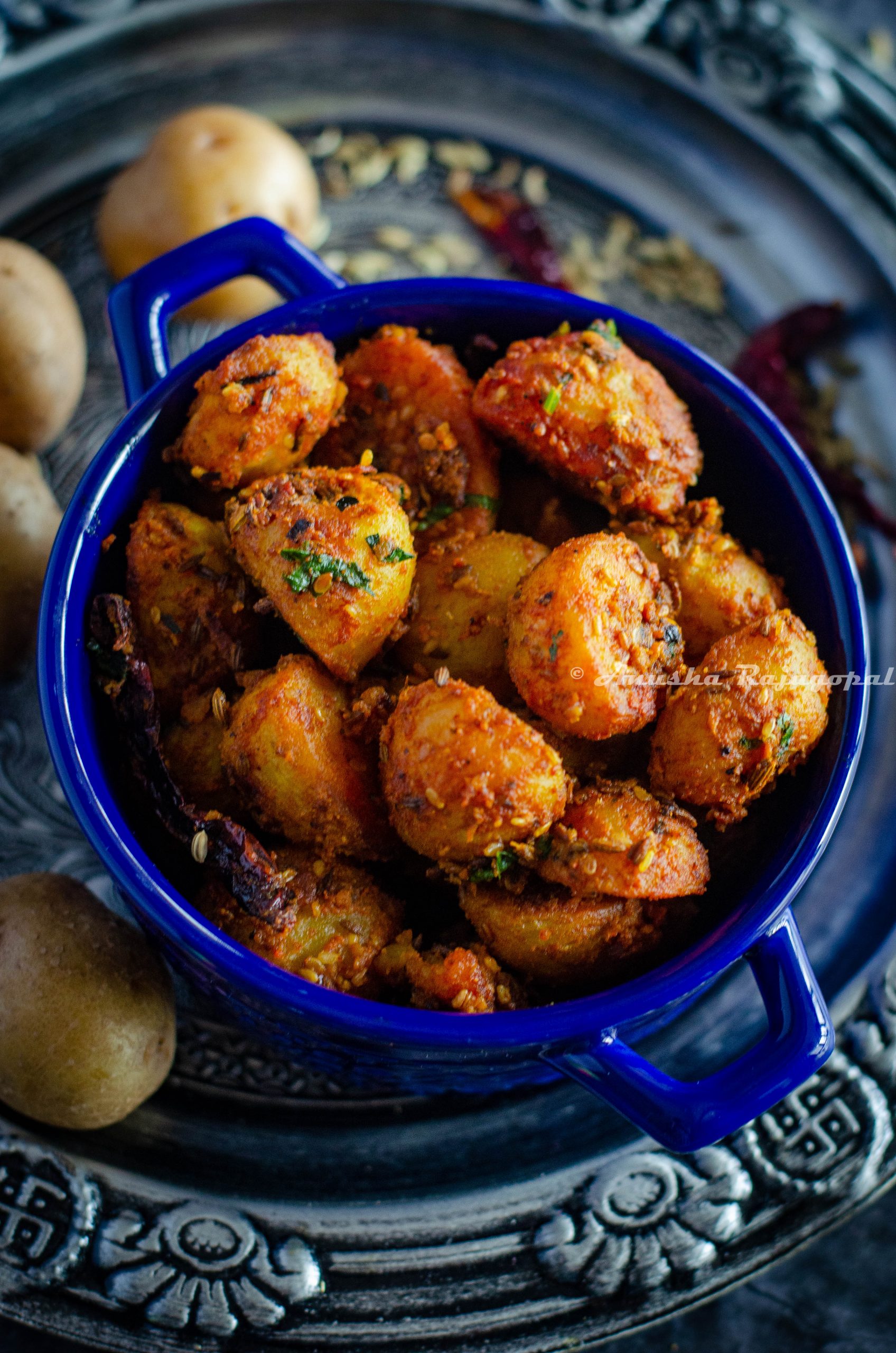 Jodhpuri aloo served in a blue casserole bowl placed over a silver plate