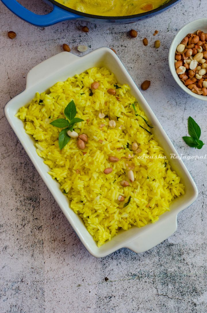 turmeric basil fried rice served in a rectangular baking tray with peanuts in a bowl by the side