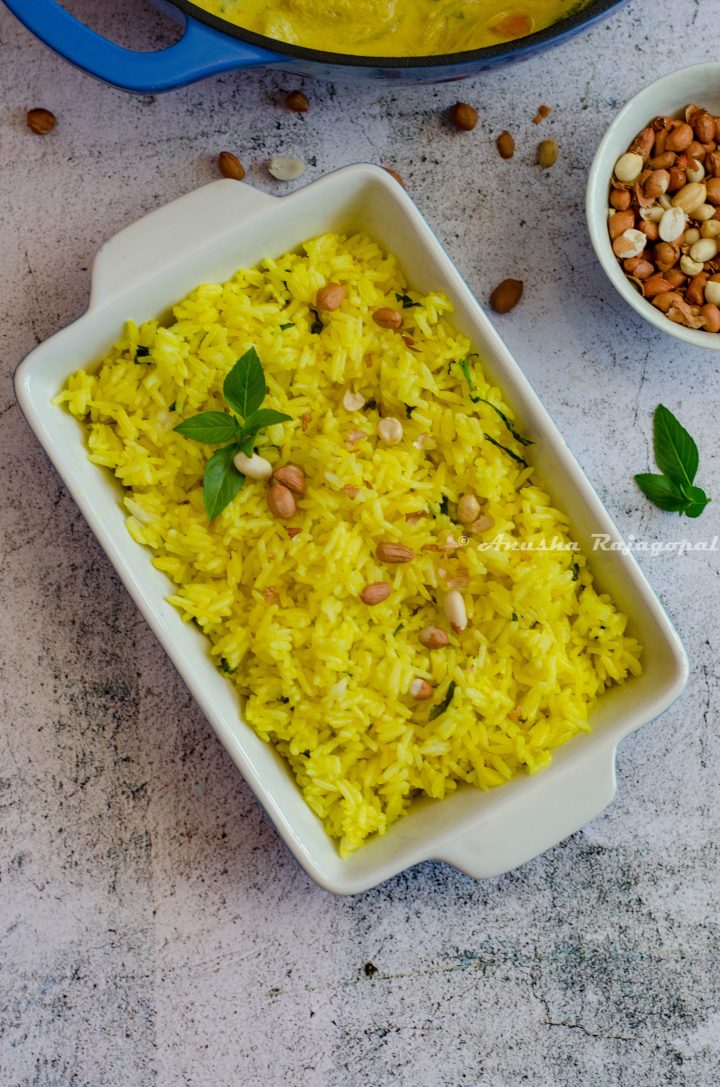 turmeric basil fried rice served in a rectangular baking tray with peanuts in a bowl by the side