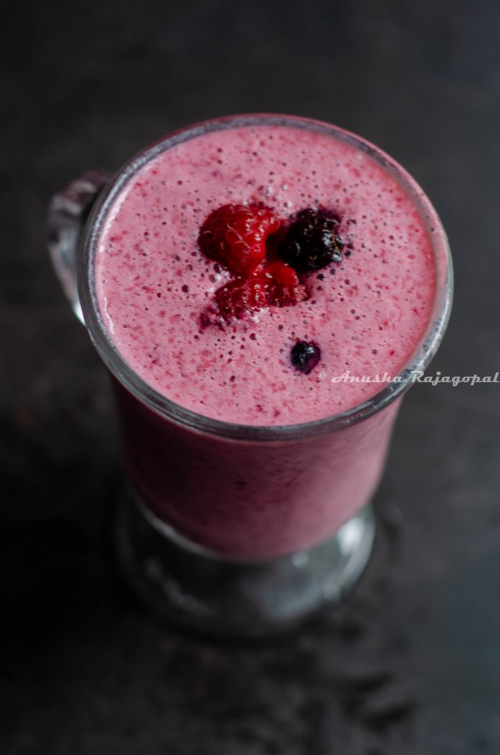 vegan berry rose lassi served in a tall glass placed on a black table