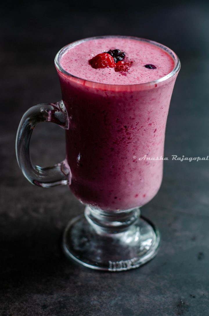 vegan berry rose lassi served in a tall glass placed on a black table