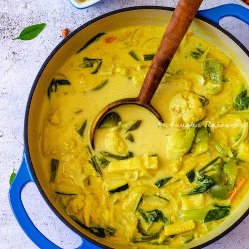 vegan thai yellow curry served in a pan with a wooden ladle