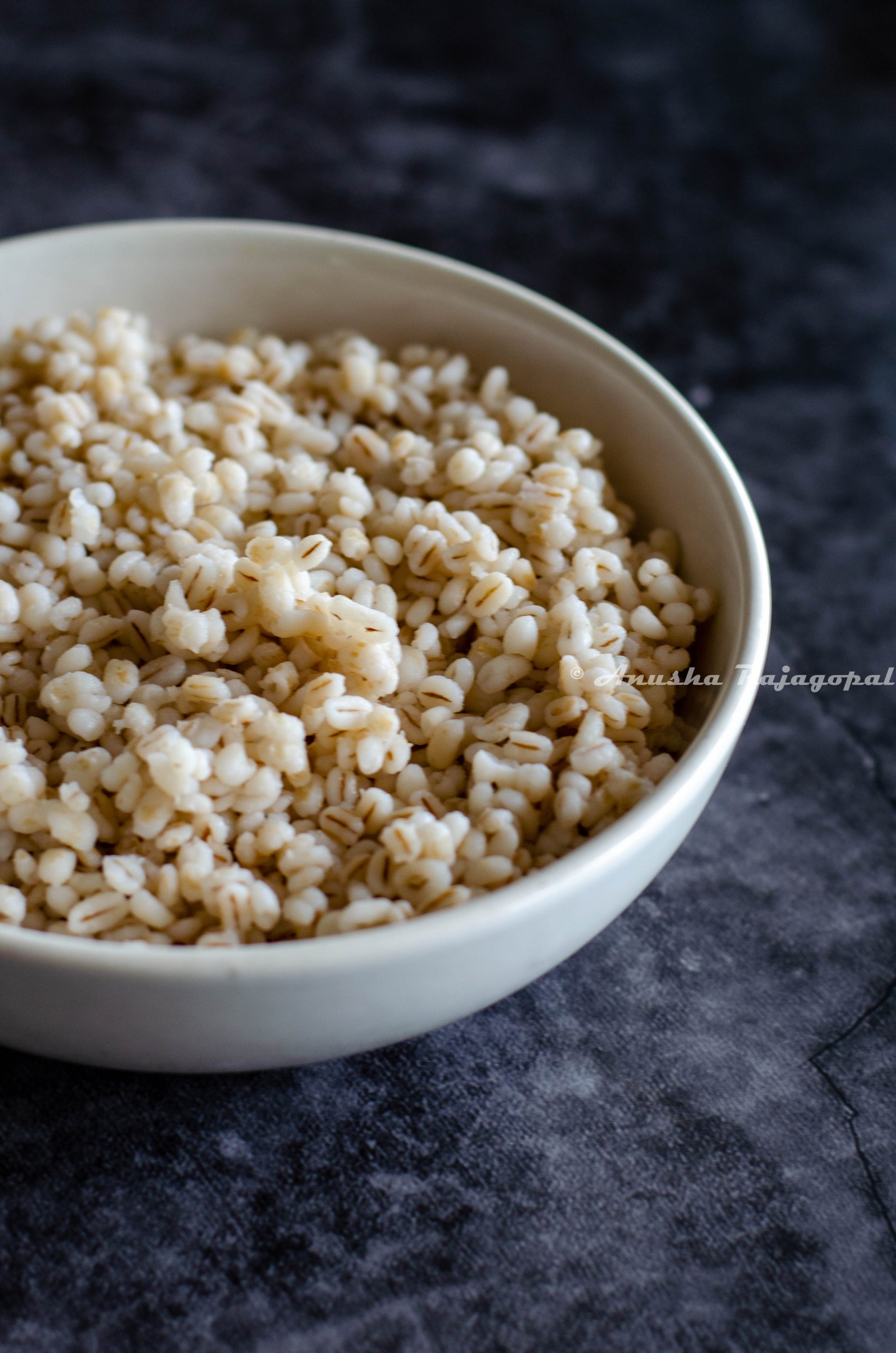 pearl barley cooked in instant pot and served in a white bowl placed over a grey backdrop