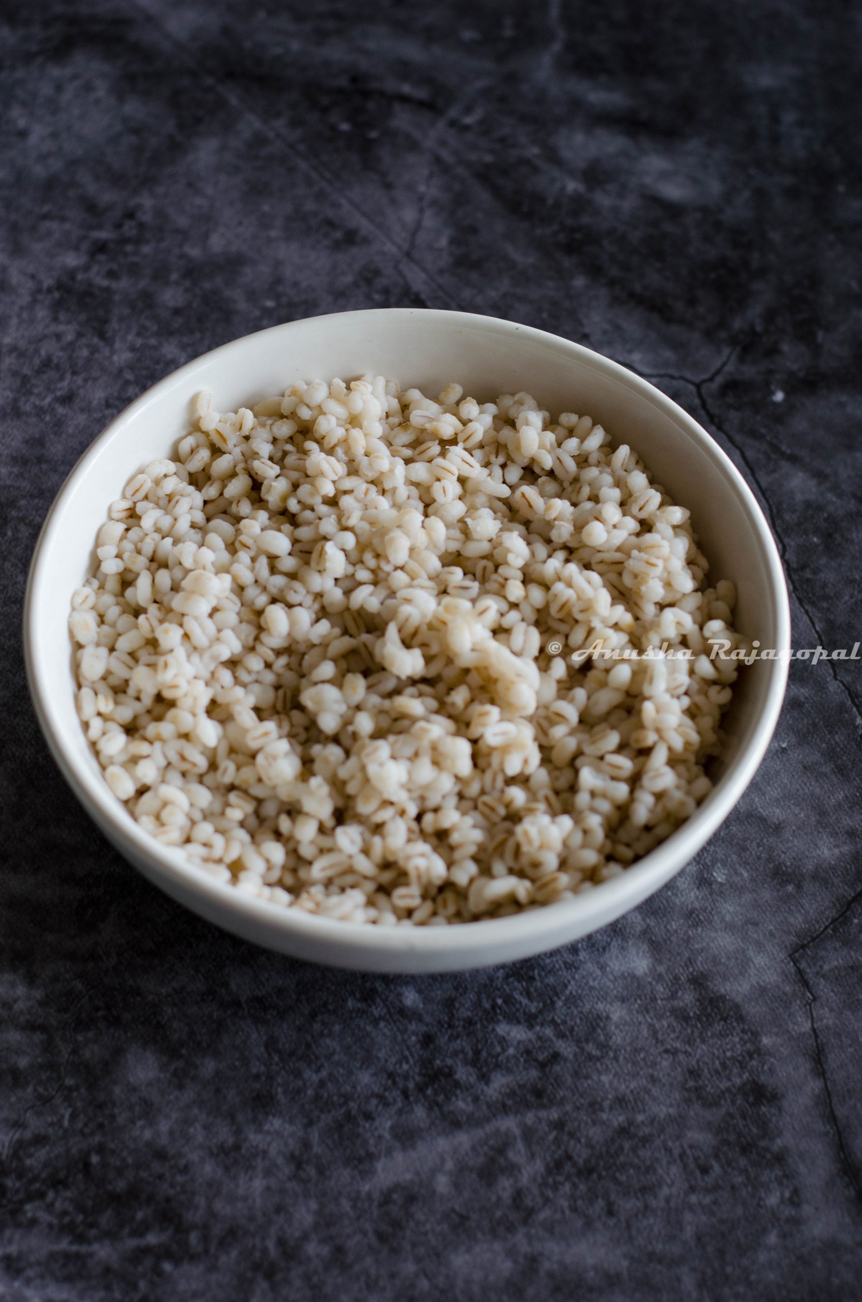 pearl barley cooked in instant pot and served in a white bowl placed over a grey backdrop