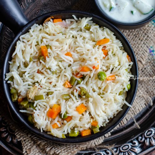 instant pot vegetable pulao in a black bowl served with cucumber raita. both bowls placed on a burlap mat over a rustic platter.