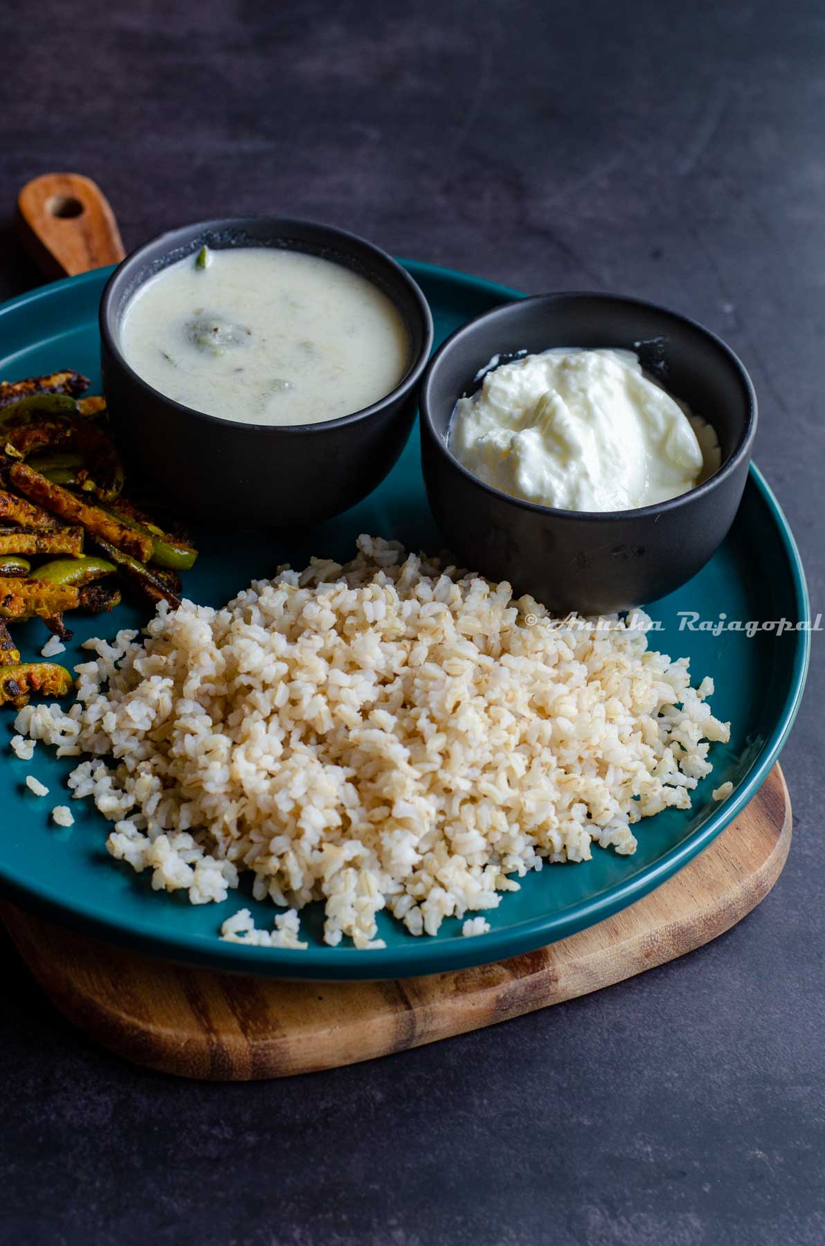 brown sona masoori rice cooked in instant pot served in a grey bowl with curry and veggies