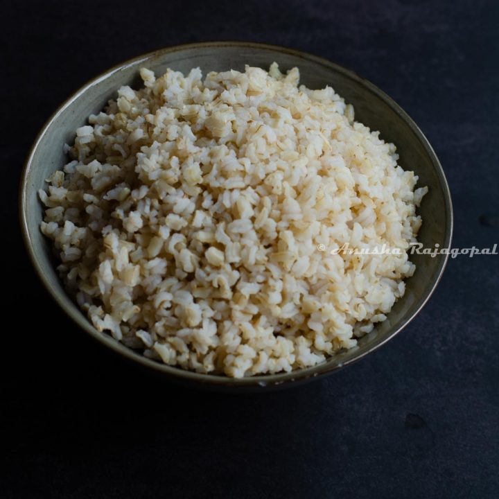 brown sona masoori rice cooked in instant pot served in a grey bowl set against a black background