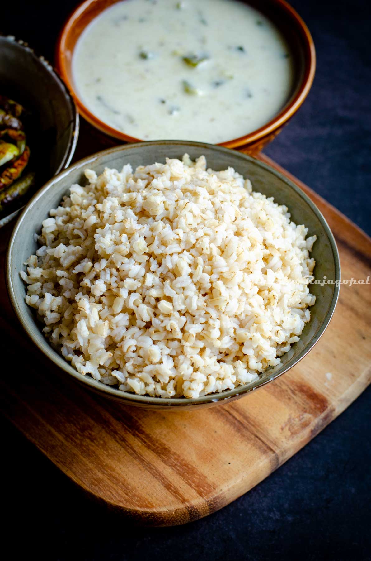brown sona masoori rice cooked in instant pot served in a grey bowl with curry and veggies