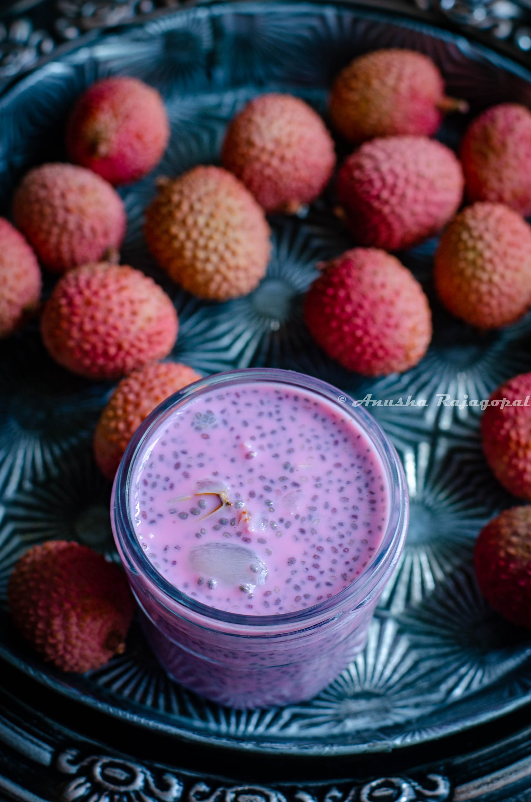 Lychee rose chia pudding in a glass jar surrounded by lychees on an vintage platter