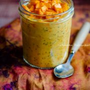 mango coconut overnight oats in a jar placed on a tie-dye towel with a spoon beside.