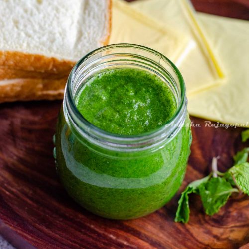 bombay sandwich chutney in a glass jar with cheese slices, herbs and bread slices around