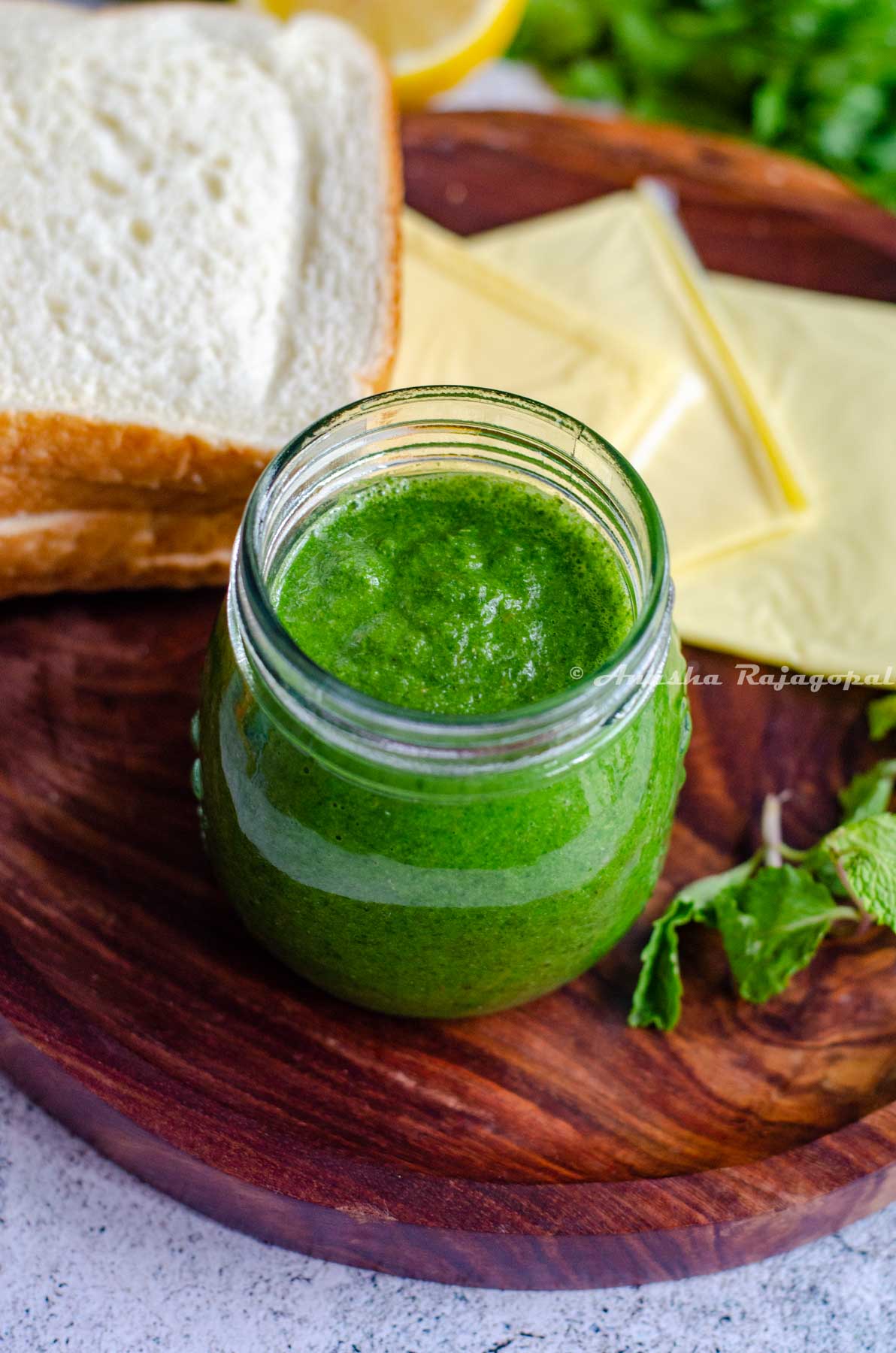 bombay sandwich chutney in a glass jar with cheese slices, herbs and bread slices around