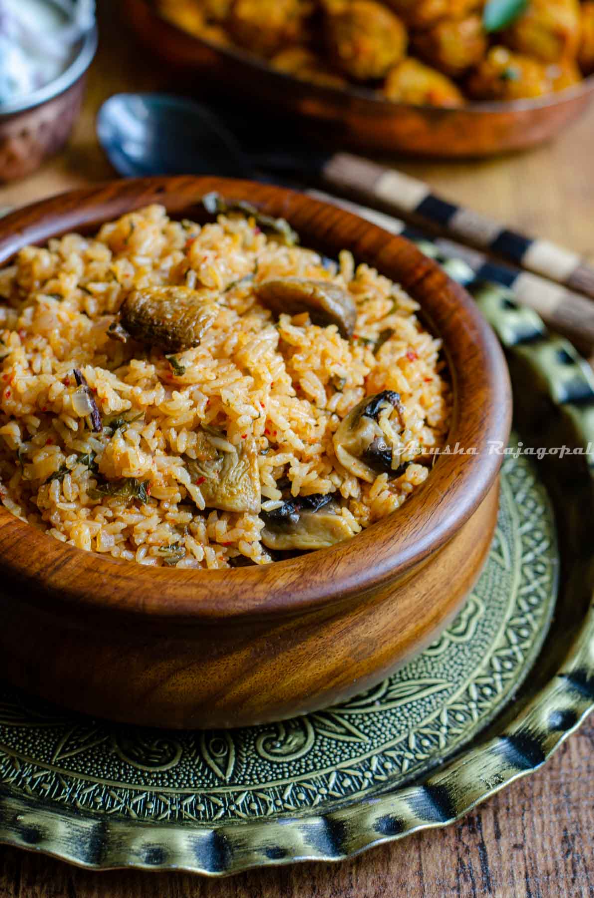 instant pot seeraga samba biryani served in a wooden handi bowl with cutlery by the side.