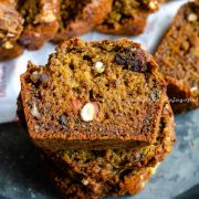 vegan zucchini bread studded with nuts, sliced and stacked in a pile.