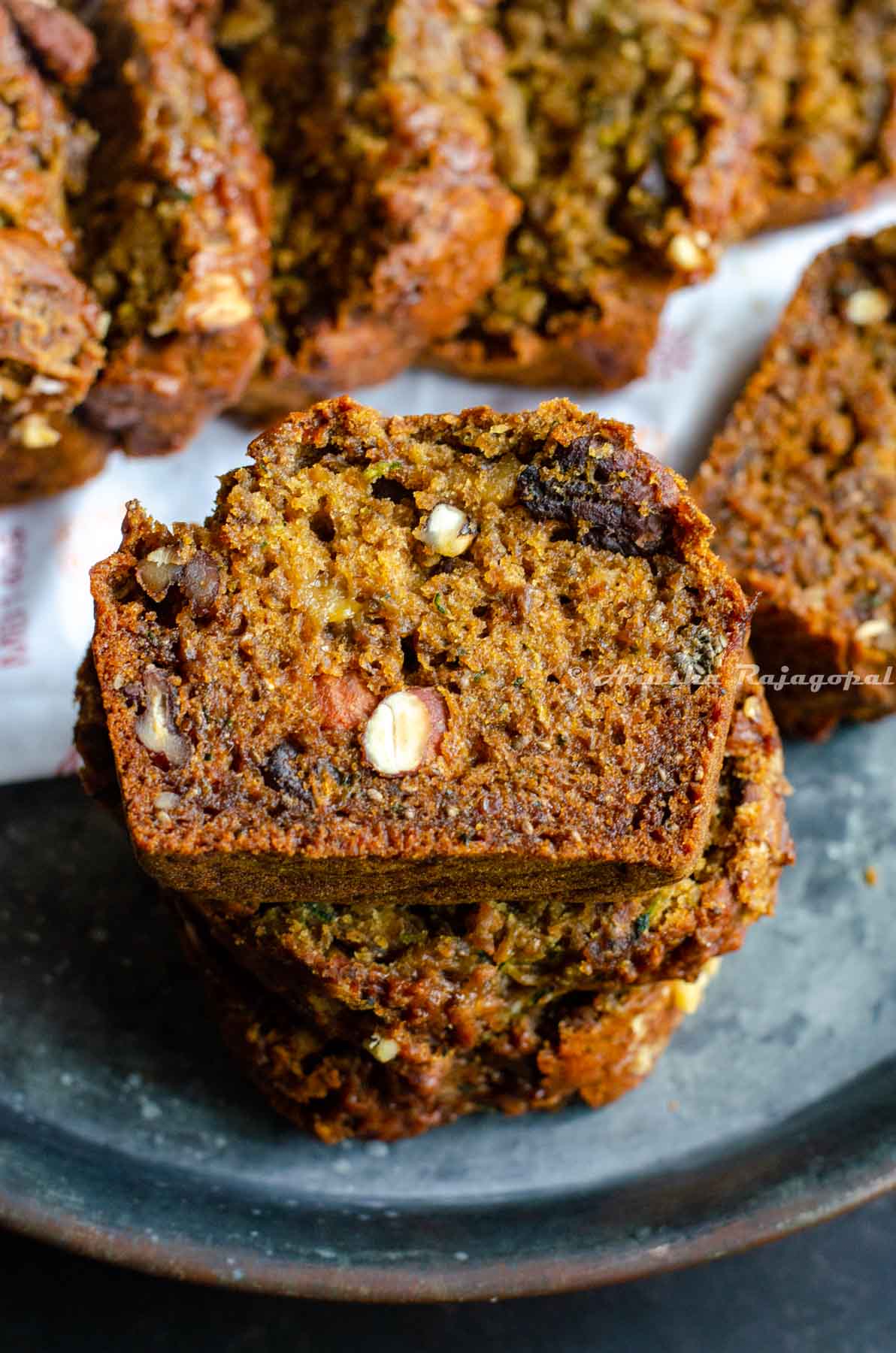 vegan zucchini bread studded with nuts, sliced and stacked in a pile.