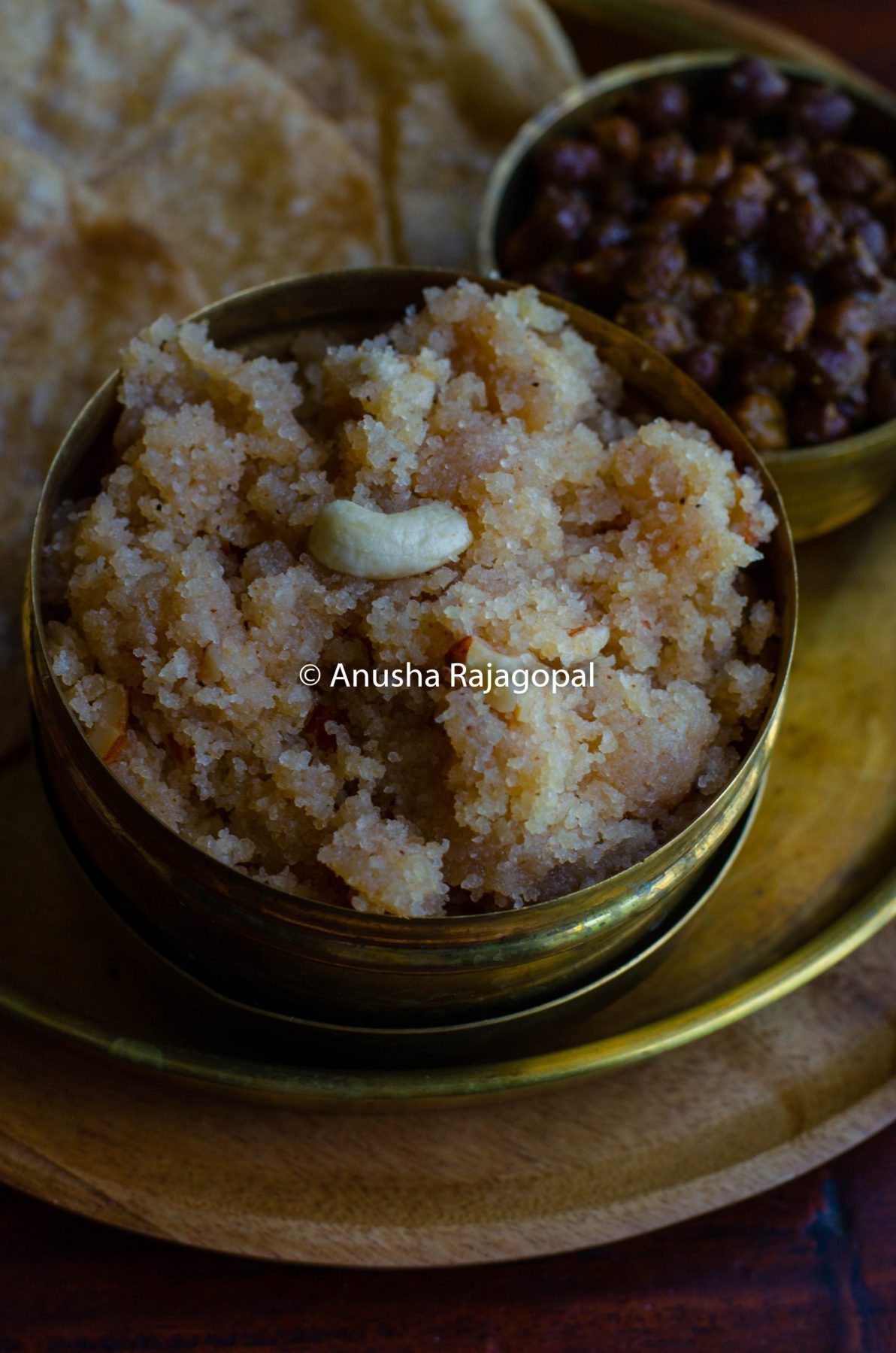 sooji ka halwa served in a brass lunch box placed on a brass platter.