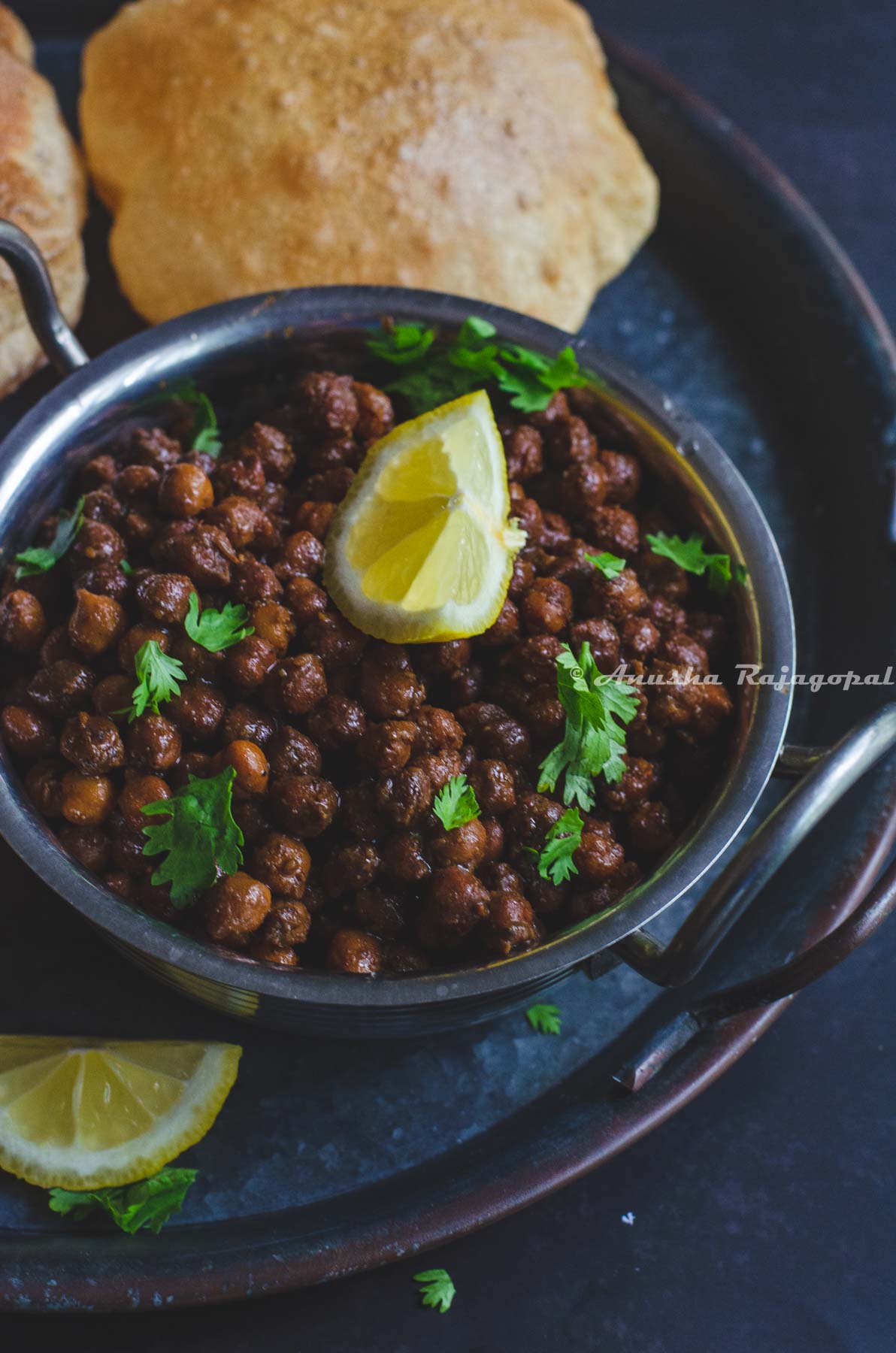 Instant Pot Sookhe Kala Chana served with a lemon wedge on top and Puri by the side