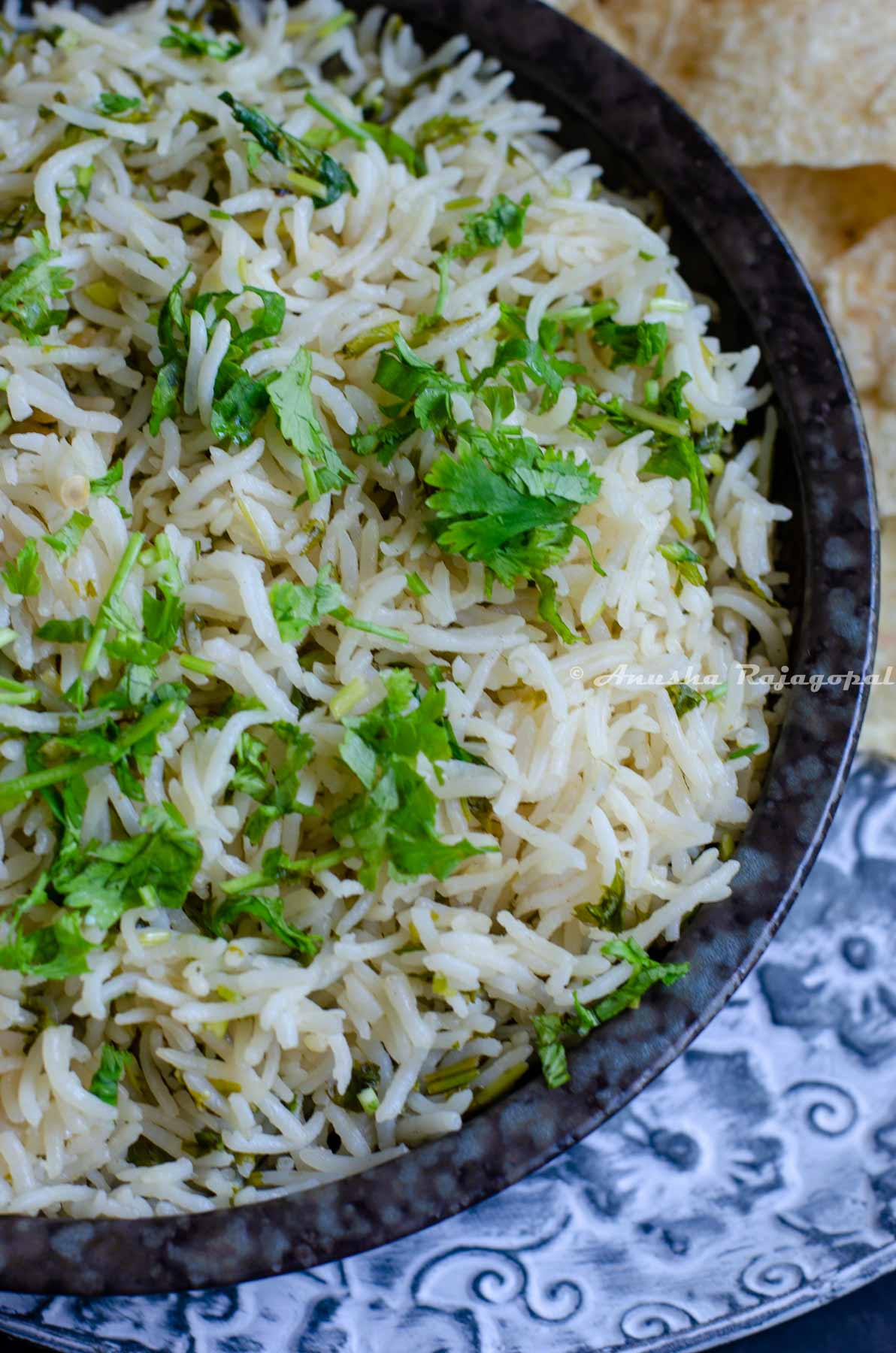 a close up shot of cilantro lime rice in a black dish placed over a metal serving tray