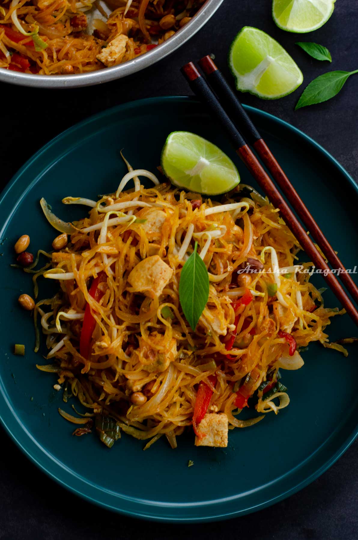 Spaghetti Squash Pad Thai served on a teal blue plate with a lime wedge and chopsticks