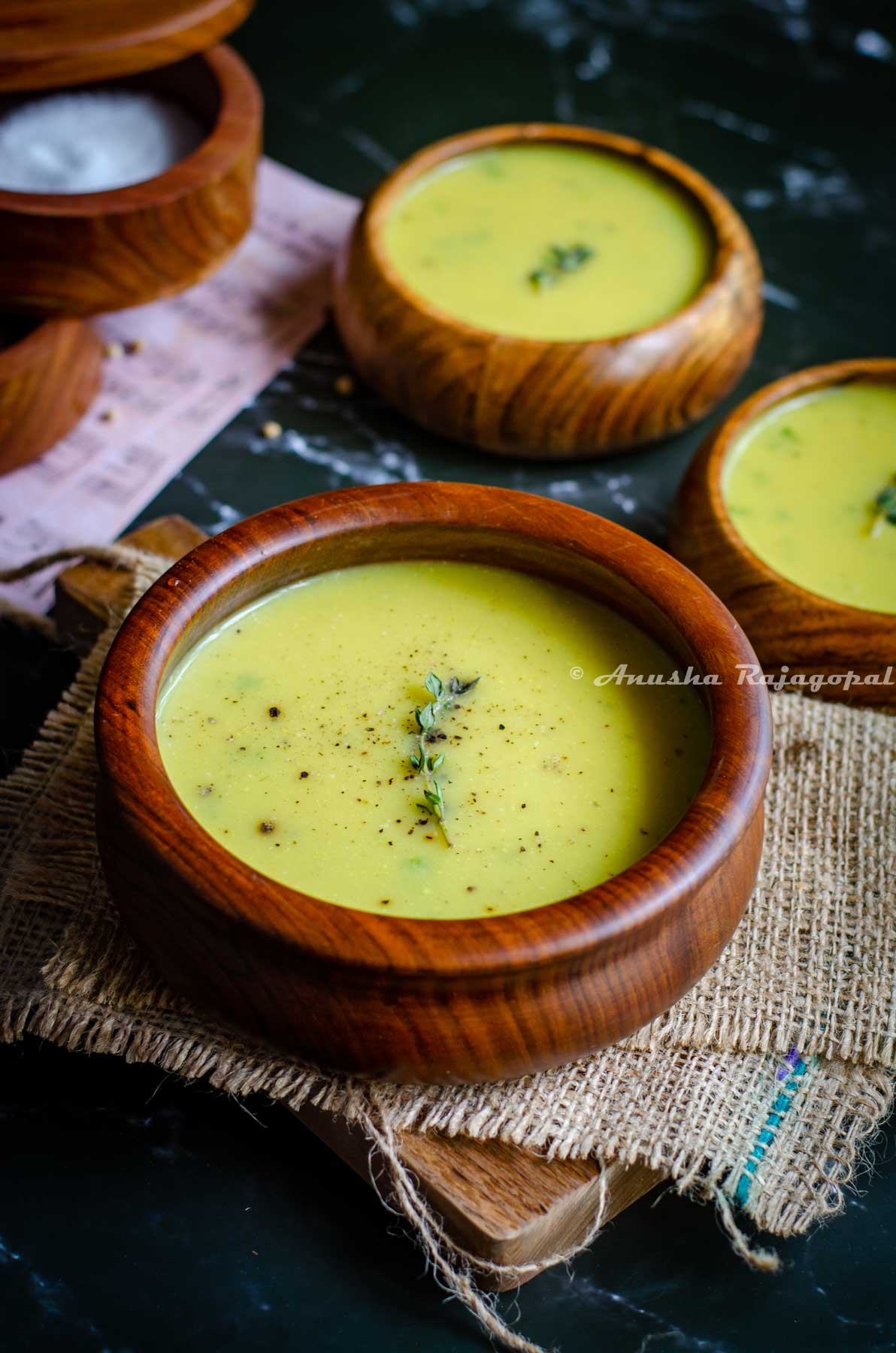 Instant pot cauliflower soup garnished with thyme and served in wooden bowls placed on a burlap mat.