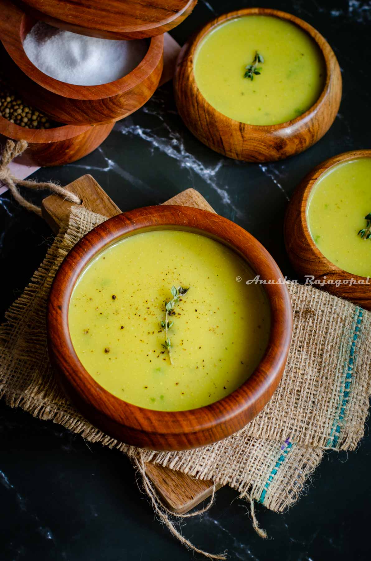 Instant pot cauliflower soup garnished with thyme and served in wooden bowls placed on a burlap mat.