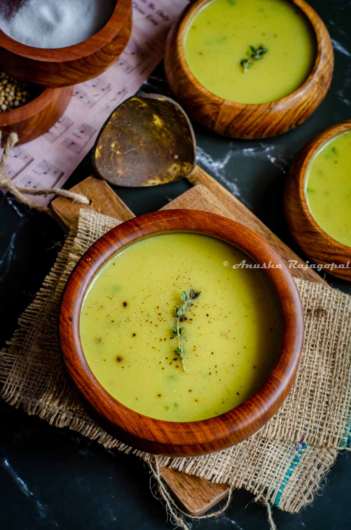 Instant pot cauliflower soup garnished with thyme and served in wooden bowls placed on a burlap mat.