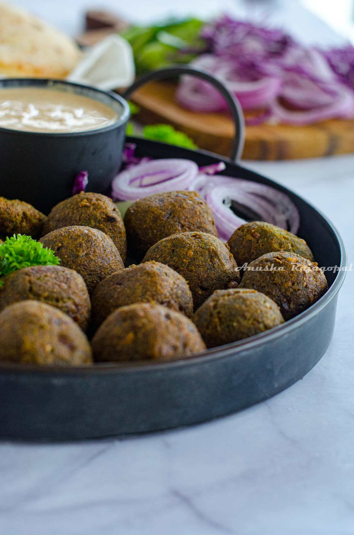 deep fried falafels on a metal tray with veggies and a dip