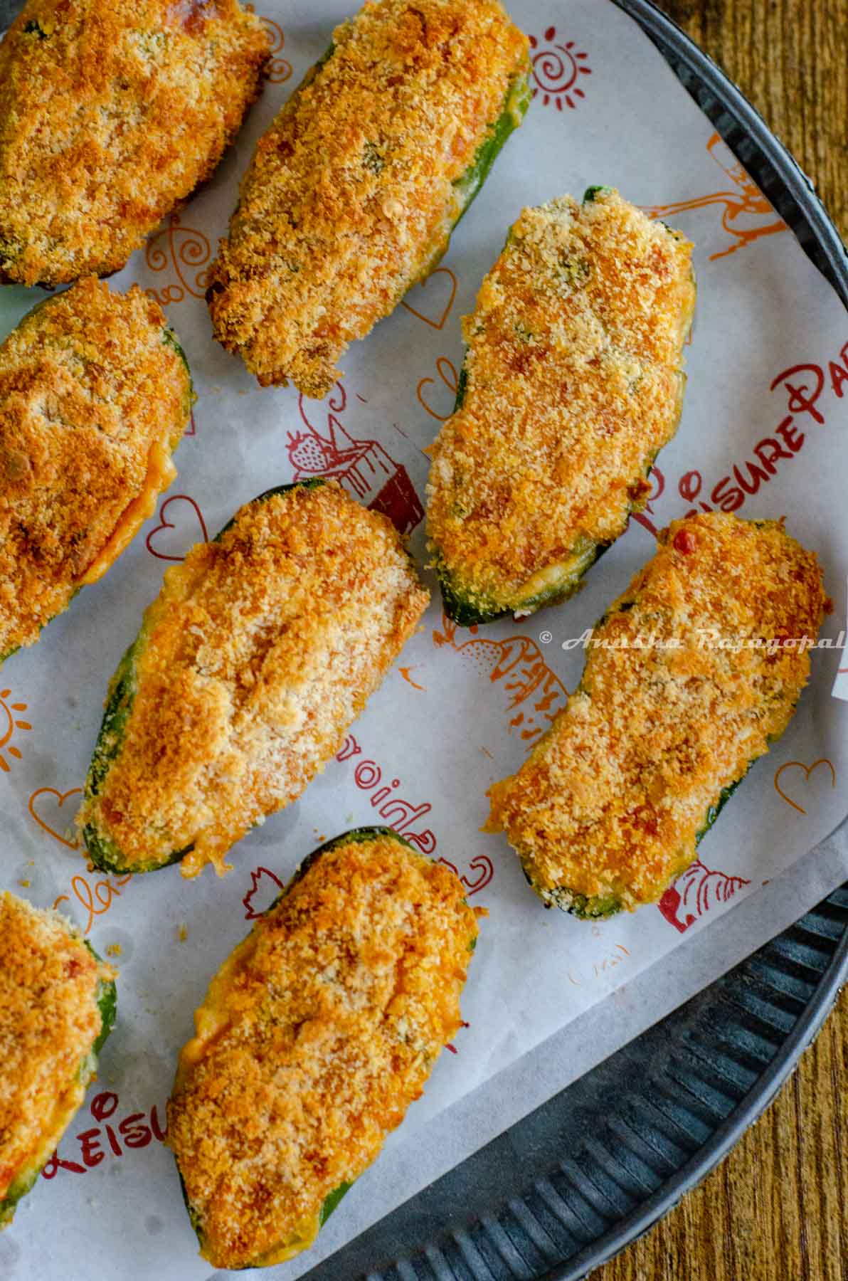 jalapeno cheese poppers air fried and served with a vegan ranch dip. These fried poppers are placed on a baking sheet laid out on a rustic metal tray.