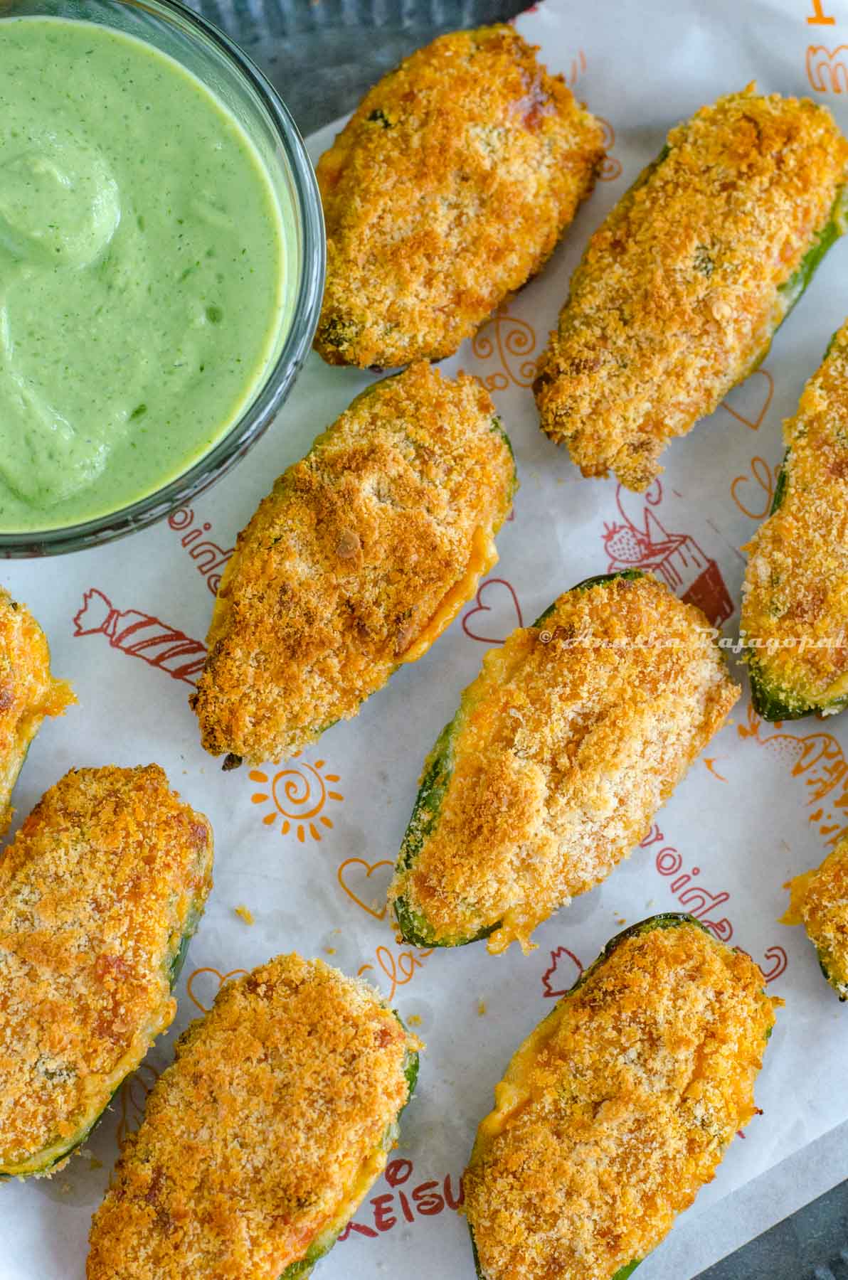 jalapeno cheese poppers air fried and served with a vegan ranch dip. These fried poppers are placed on a baking sheet laid out on a rustic metal tray.