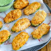 jalapeno cheese poppers air fried and served with a vegan ranch dip. These fried poppers are placed on a baking sheet laid out on a rustic metal tray.