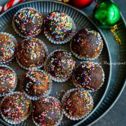 chocolate mint truffles shaped and placed in small muffin cups and arranged on a metal serving tray. Christmas tree decor at the background.