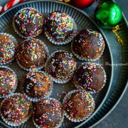 chocolate mint truffles shaped and placed in small muffin cups and arranged on a metal serving tray. Christmas tree decor at the background.