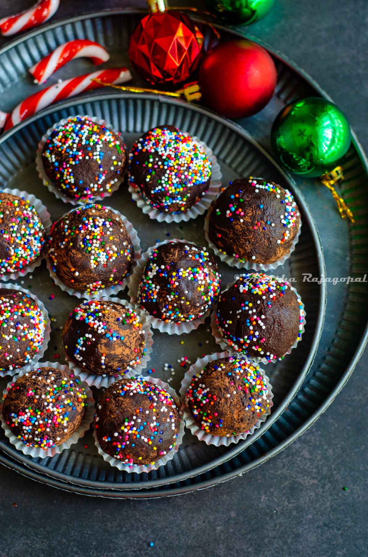 chocolate mint truffles shaped and placed in small muffin cups and arranged on a metal serving tray. Christmas tree decor at the background.