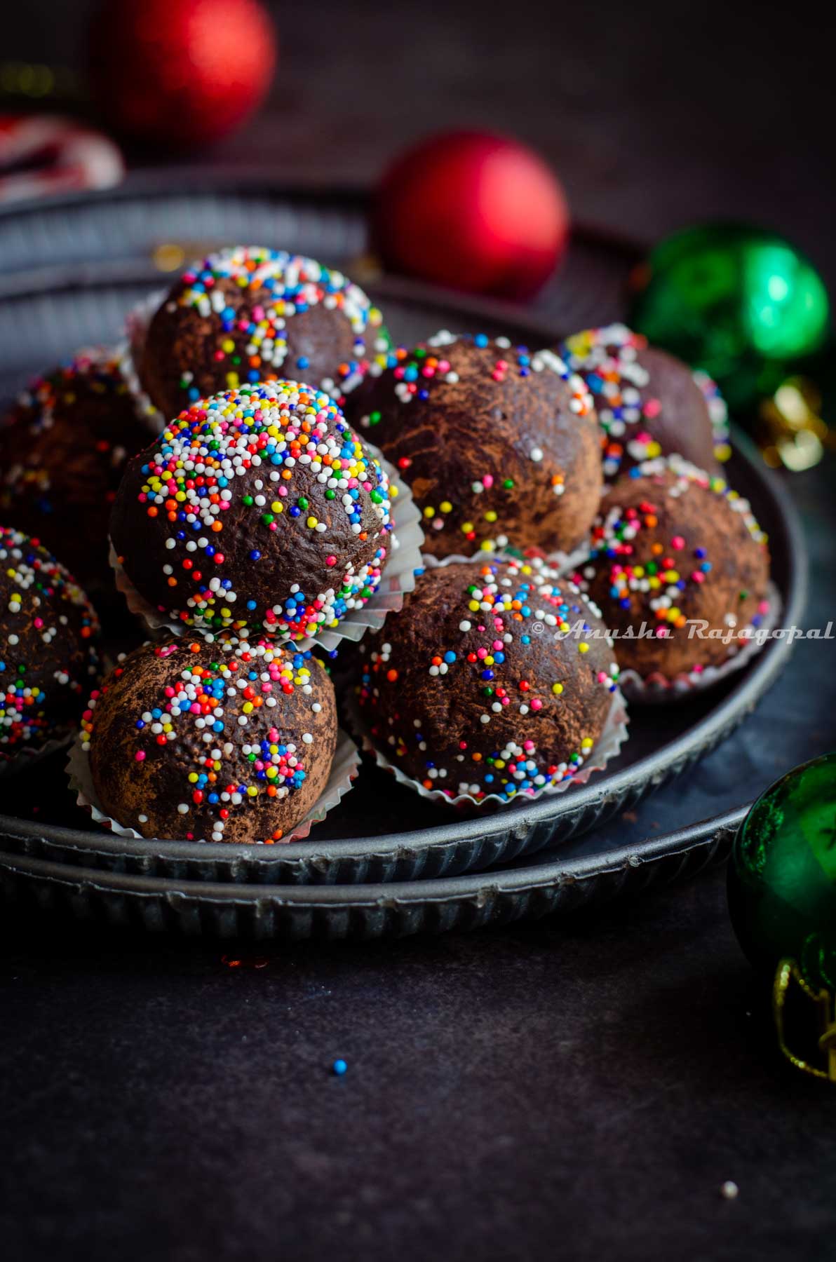 chocolate mint truffles shaped and placed in small muffin cups and arranged on a metal serving tray. Christmas tree decor at the background.