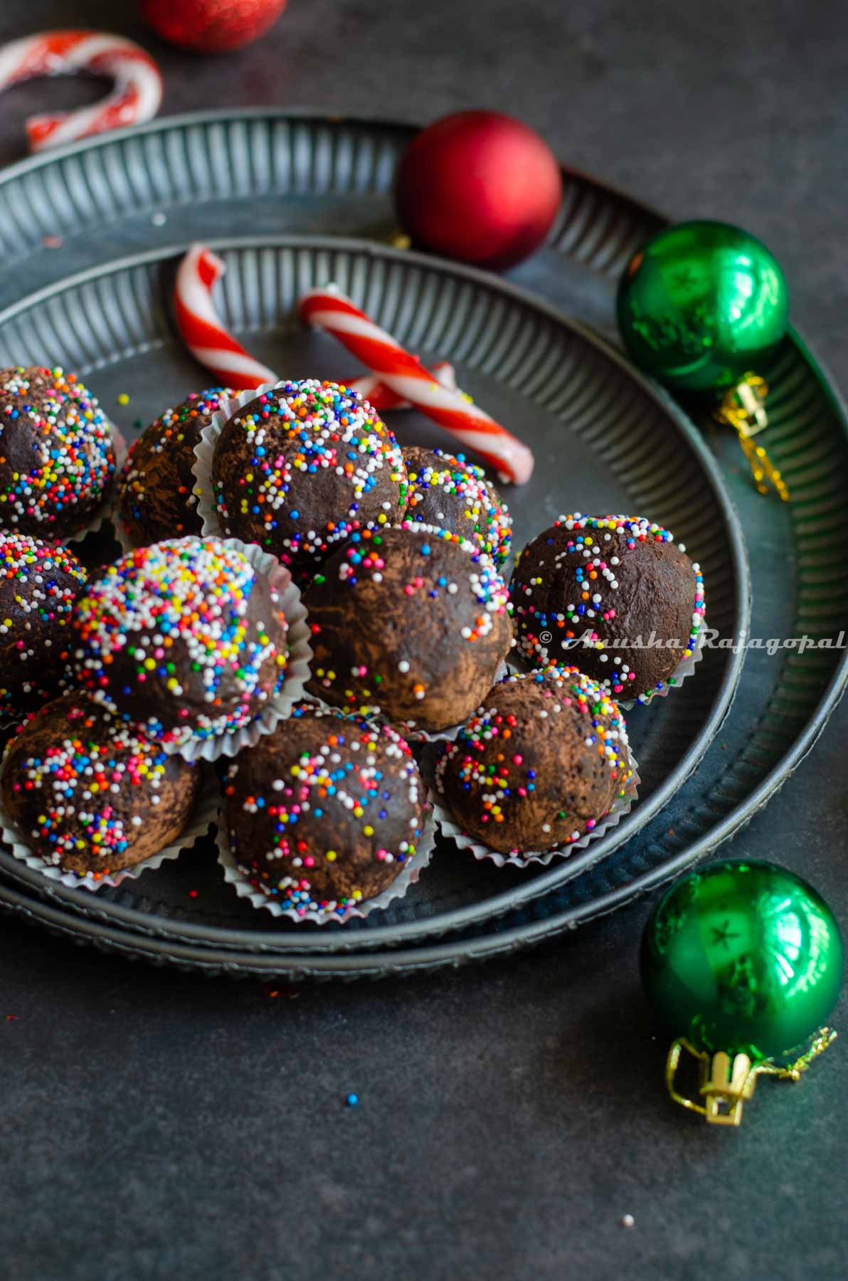 chocolate mint truffles shaped and placed in small muffin cups and arranged on a metal serving tray. Christmas tree decor at the background.