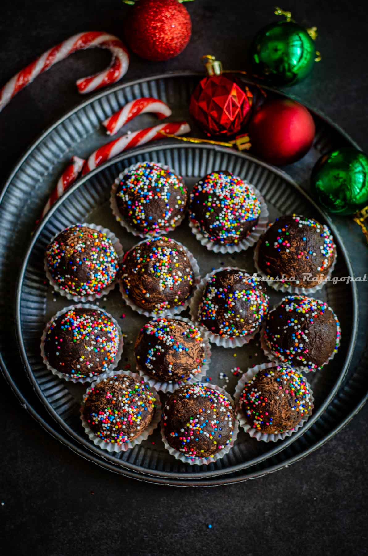 chocolate mint truffles shaped and placed in small muffin cups and arranged on a metal serving tray. Christmas tree decor at the background.