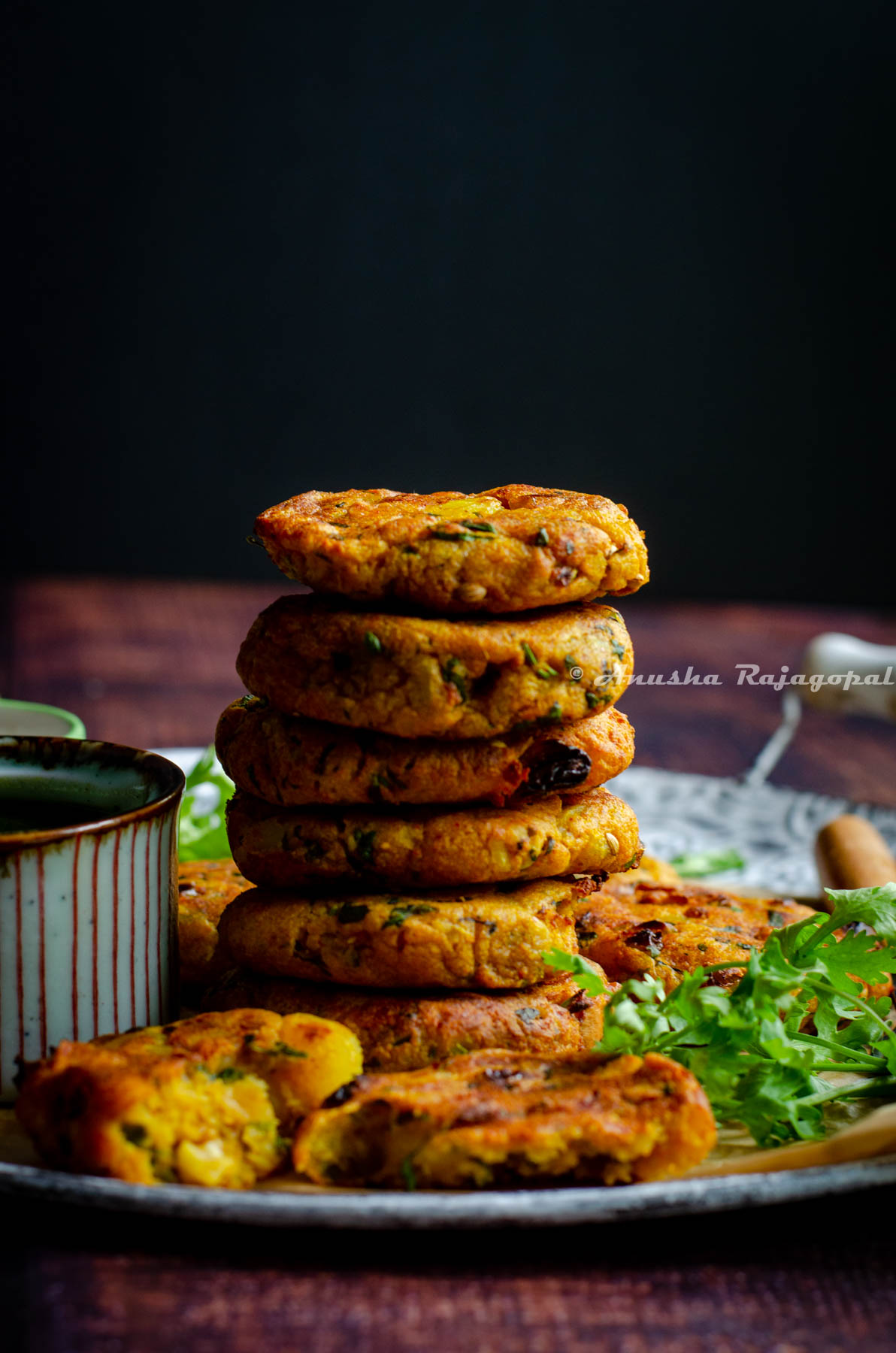Aloo and Paneer Tikkis stacked in a pile and served on a rustic serving platter with condiments by the side.