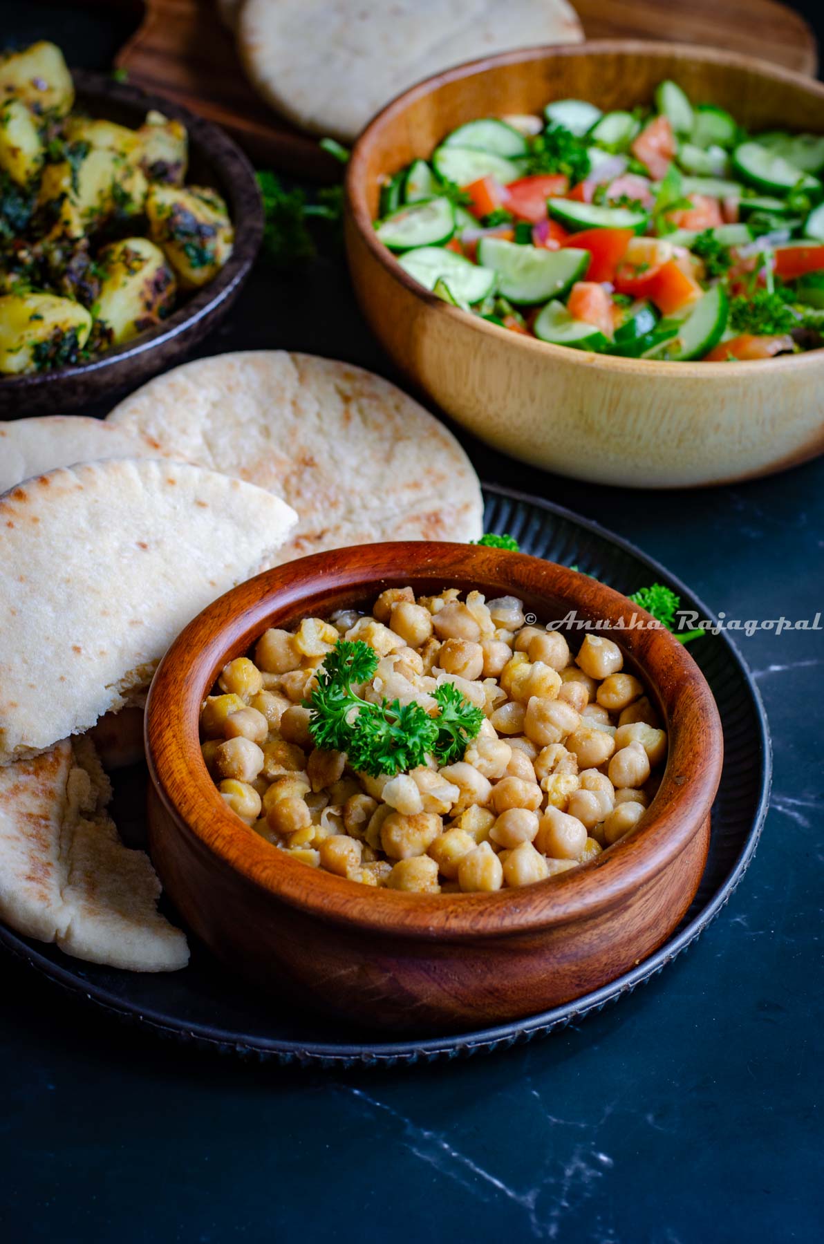 hummus balila served in a wooden bowl with pita bread and shirazi salad