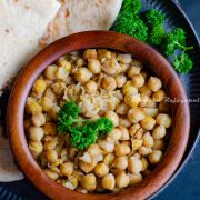 hummus balila served in a wooden bowl with pita bread and shirazi salad