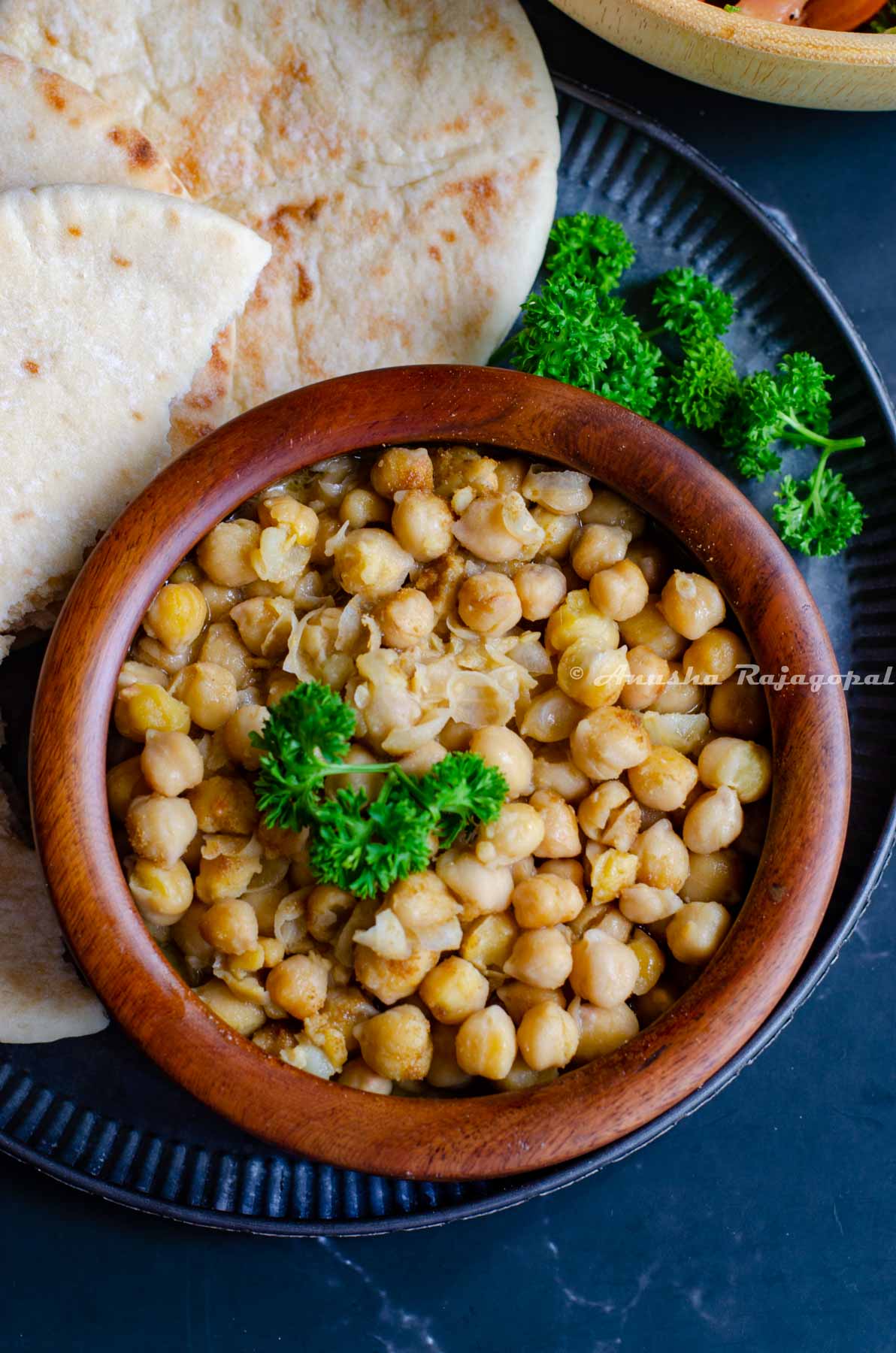 hummus balila served in a wooden bowl with pita bread and shirazi salad