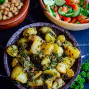 Lebanese batata harra served in a black bowl with Balila and Shirazi salad.