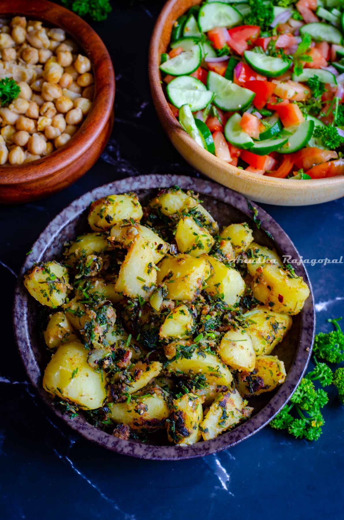 Lebanese batata harra served in a black bowl with Balila and Shirazi salad.