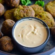 easy 5 minute tahini yogurt sauce served in a small black dip bowl with falafel