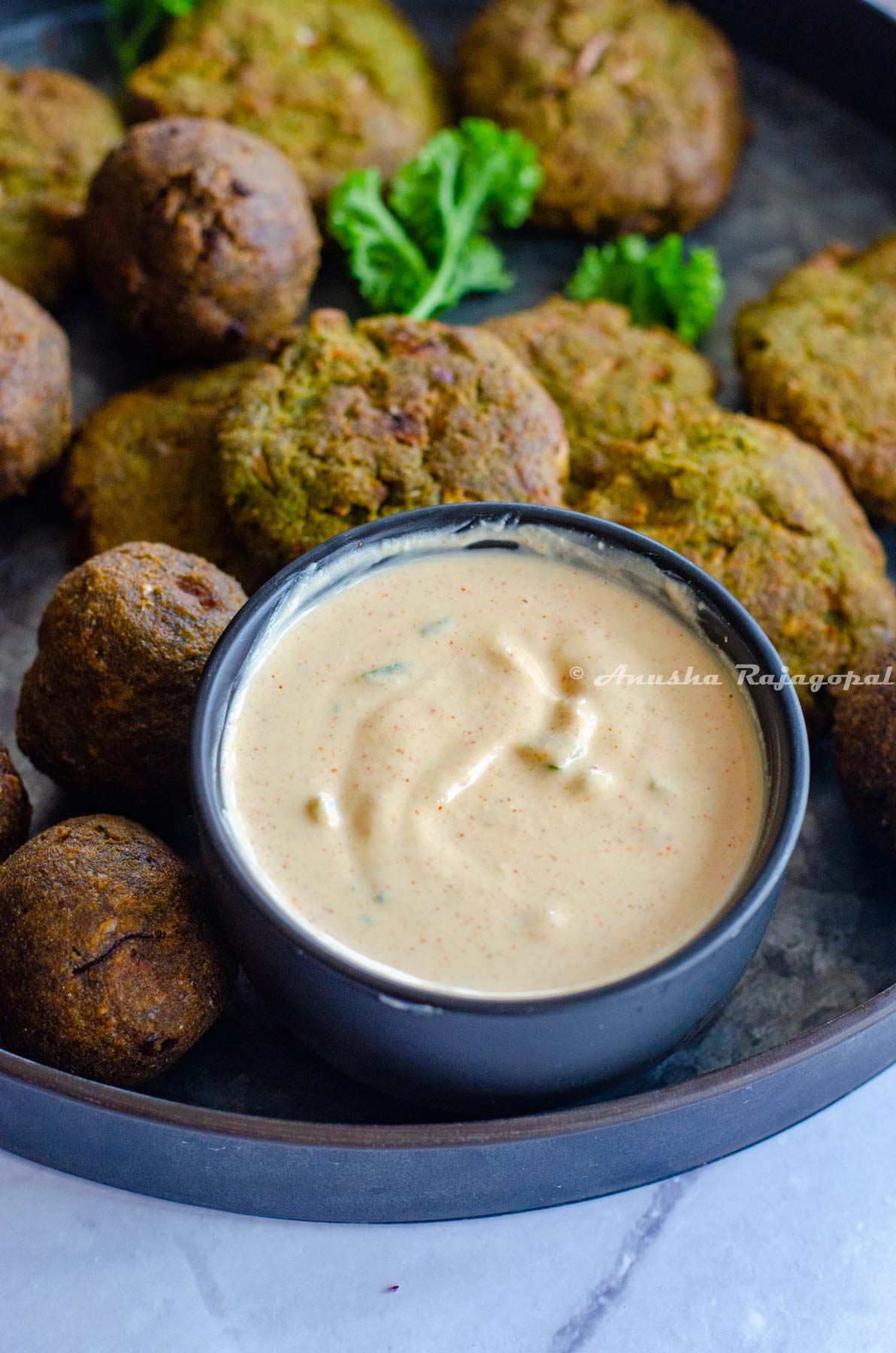 easy 5 minute tahini yogurt sauce served in a small black dip bowl with falafel